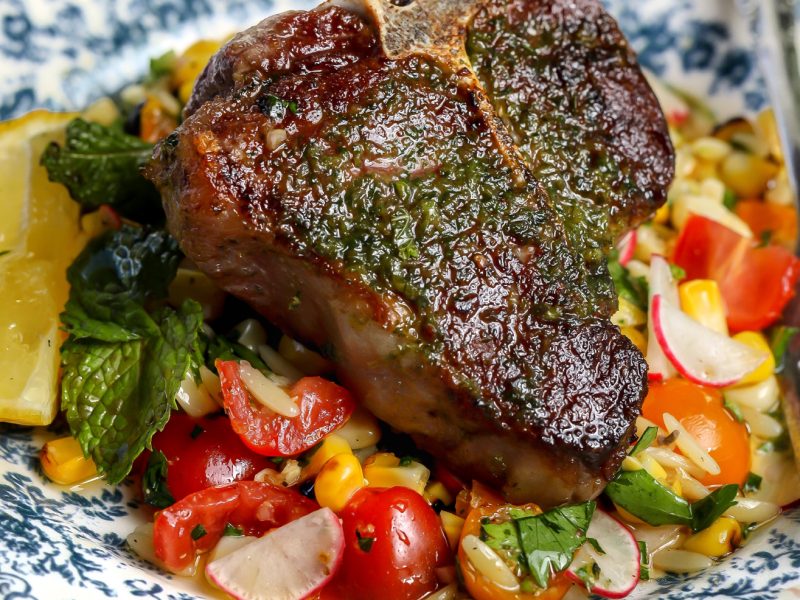 Lamb loin chops served over grilled corn and orzo salad with tomatoes and fresh herbs