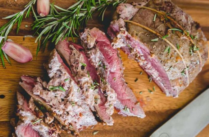 butterflied leg of lamb with cranberry goat cheese stuffing cooked and cut on cutting board