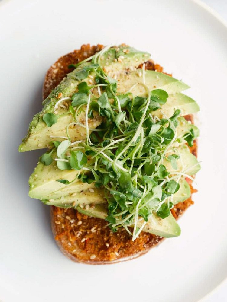 Close up of California Lamb avocado toast with microgreens and seasoning