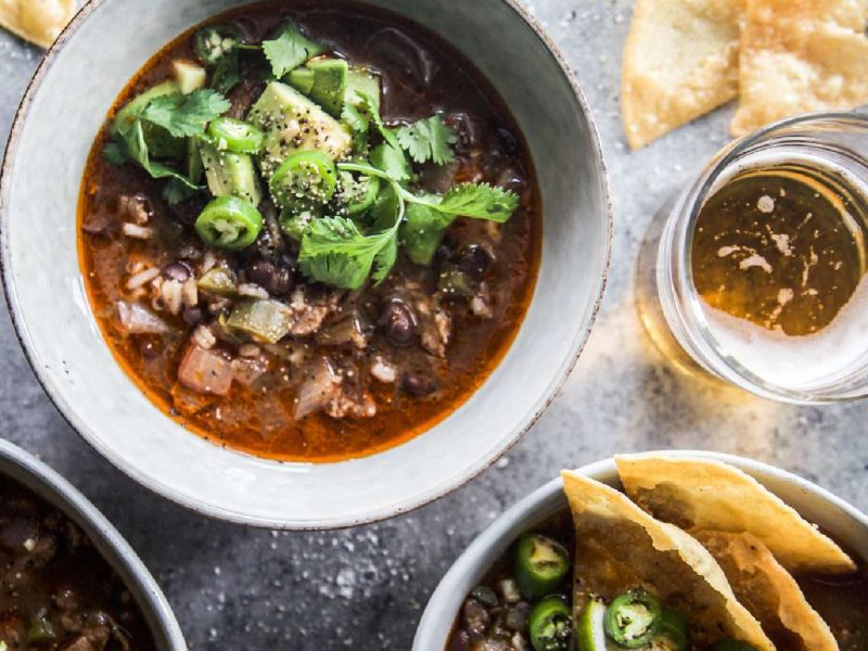 Slow cooker lamb shoulder Tex Mex tortilla soup with cilantro and tortilla chips in serving bowls