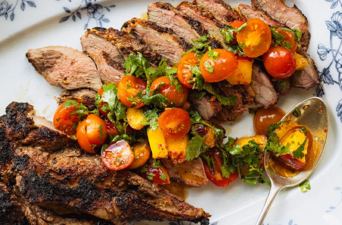 Marinated grilled American lamb topped with nectarine and tomato salad on a serving platter