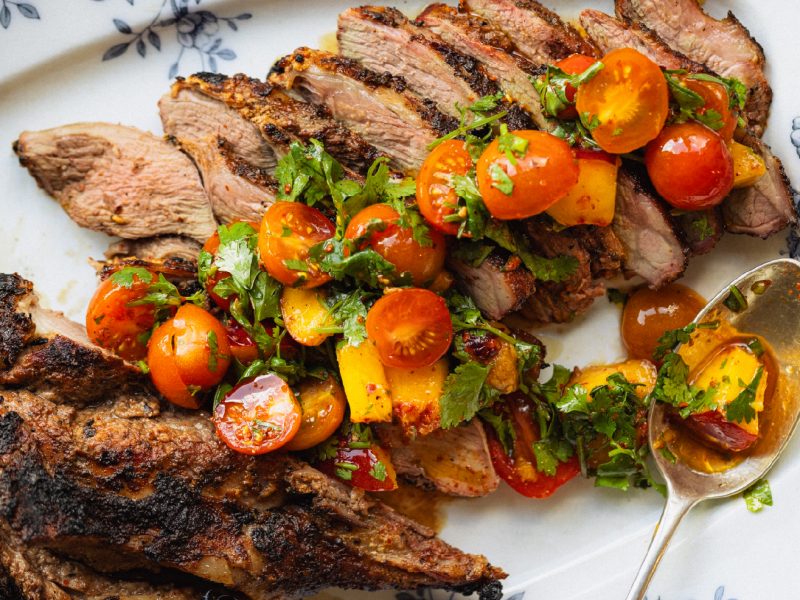Marinated grilled American lamb topped with nectarine and tomato salad on a serving platter