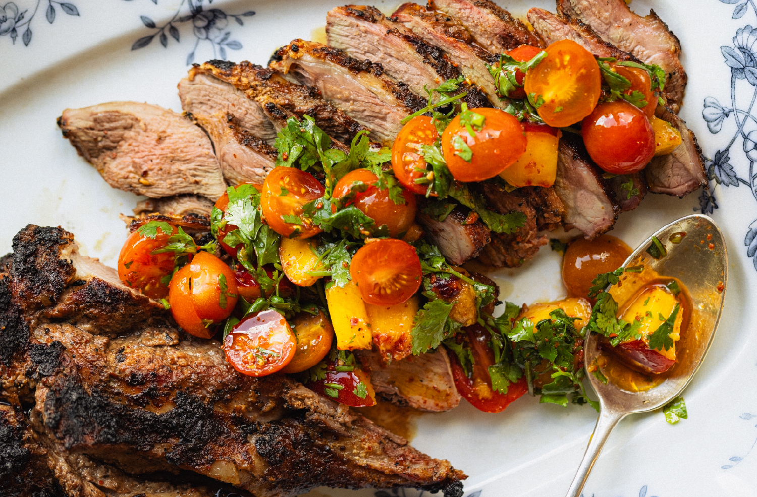 Marinated grilled American lamb topped with nectarine and tomato salad on a serving platter